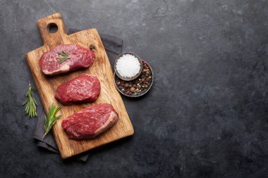 Fileminyon taze çiğ biftek ve kesme tahtasında baharatlar. Üst görünüm düzlüğü kopyalama alanı ile yatıyordu