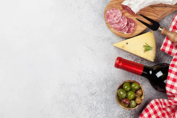 Italian cuisine food. Cheese, salami, olives and wine. Top view flat lay on stone table with copy space