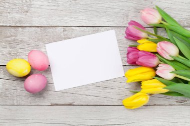 Paskalya tebrik kartı, üzerinde paskalya yumurtaları ve lale çiçekleri var. Üst görünüm düzlüğü kopyalama alanı ile yatıyordu