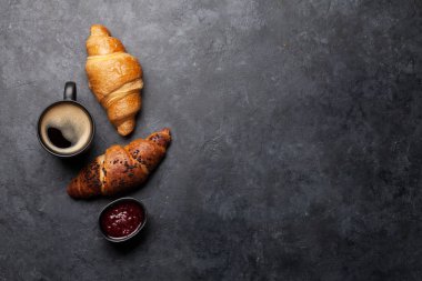 Kahve fincanı ve kruvasanla kahvaltı. Taş masadaki en üst manzara. Kopyalama alanı olan düz