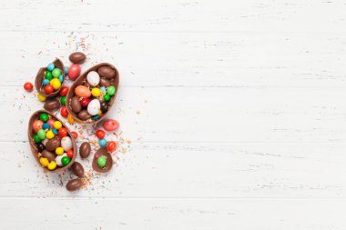 Çikolatalı paskalya yumurtaları ve ahşap arkaplan tebrik kartında renkli tatlılar. Üst Manzara. Selamlarınız için uzayı olan düz uzanın