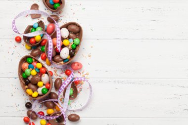 Çikolatalı paskalya yumurtaları ve ahşap arkaplan tebrik kartında renkli tatlılar. Üst Manzara. Selamlarınız için uzayı olan düz uzanın