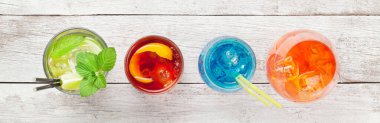 Beyaz ahşap masada dört klasik kokteyl bardağı. Negroni, mavi lagün, aperol spritz ve mojito. Üst Manzara. Düz yatıyordu