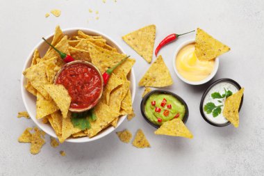 Çeşitli soslu Meksika cipsi. Guacamole, salsa, peynir ve ekşi krema. Üst görünüm düz taş masa üzerinde yatıyordu