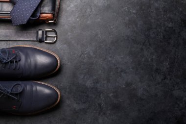 Kravat, kemer, ayakkabı ve çanta gibi klasik erkek kıyafetleri fotokopi alanı ile taştan arka planda. Üst görünüm düzlüğü