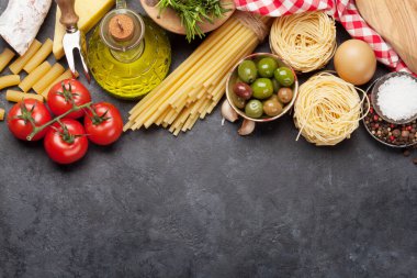 İtalyan mutfağı malzemeleri. Makarna, peynir, zeytin ve domates. Üst görünüm düz taş masa üzerinde kopya alanı ile yatıyordu