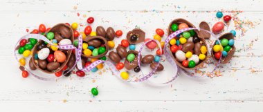 Çikolatalı paskalya yumurtaları ve ahşap arkaplan tebrik kartında renkli tatlılar. Üst Manzara. Düz yatıyordu