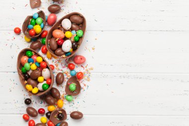 Çikolatalı paskalya yumurtaları ve ahşap arkaplan tebrik kartında renkli tatlılar. Üst Manzara. Selamlarınız için uzayı olan düz uzanın