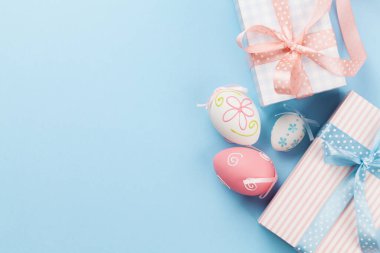Hediye kutularıyla Paskalya tebrik kartı ve mavi arka planda renkli paskalya yumurtaları. Tebrik etmek için en üstteki dairede yer var.