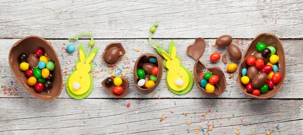 チョコレートイースターエッグやカラフルなお菓子を木の背景グリーティングカードに 最上階だ — ストック写真