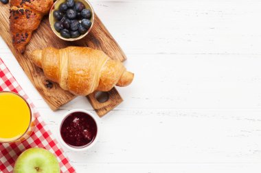 Kahveyle kahvaltı, portakal suyu ve kruvasanla. Tahta masanın üst manzarası. Kopyalama alanı olan düz