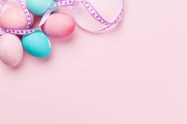 Paskalya tebrik kartı ve pembe arka planda renkli paskalya yumurtaları. Tebrik etmek için en üstteki dairede yer var.