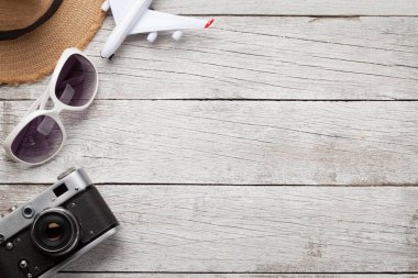 Seyahat konsepti şapka, güneş gözlüğü, kamera ve uçak oyuncaklarıyla ahşap masada. Üst görünüm düzlüğü kopyalama alanı ile yatıyordu