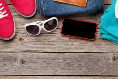 Giysiler ve aksesuarlar. Spor ayakkabı, kot pantolon, güneş gözlüğü ve akıllı telefon. Her gün için şehir kıyafeti ya da arka planda fotokopi alanı olan bir seyahat tatili. Üst görünüm düzlüğü