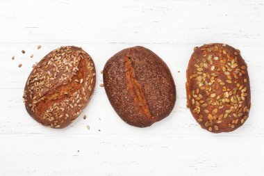 Tahta masadaki tohumlu çeşitli ev yapımı ekmek. Üst görünüm düzlüğü kopyalama alanı ile yatıyordu