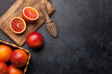 Sicilya kanı sulu portakallar ve meyve sıkacağı. Kopyalama alanı olan üst görünüm