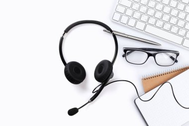 Bilgisayarı, kulaklığı ve malzemeleri olan beyaz ofis masası. Masaüstü. Uzaktan çalışma konsepti. Metnin için alanı olan en üstteki görünüm