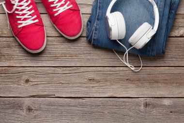 Giysiler ve aksesuarlar. Spor ayakkabı, kot pantolon ve kulaklık. Her gün için şehir kıyafeti ya da arka planda fotokopi alanı olan bir seyahat tatili. Üst görünüm düzlüğü