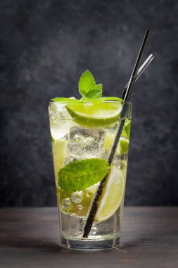 Ahşap masada klasik kokteyl camı. Limonlu ve naneli mojito.