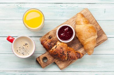 Kahveyle kahvaltı, portakal suyu ve kruvasanla. Tahta masanın üst manzarası. Düz yatıyordu