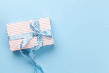 Mavi arka planda pastel renkli hediye kutusu olan tebrik kartı. Tebrik etmek için en üstteki dairede yer var.