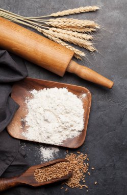 Çeşitli ekmek malzemeleri. Buğday, un ve pişirme aletleri taş masada. Üst görünüm düzlüğü