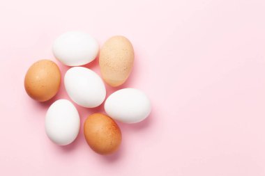 Pembe arka planda beyaz ve kahverengi tavuk yumurtaları. Paskalya tebrik kartı. Kopyalama alanı olan üst görünüm. Düz yatıyordu