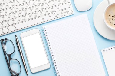 Bilgisayarlı, akıllı telefonlu, malzemeli ve kahveli mavi çalışma masası. Metnin ya da uygulaman için en üstteki görünüm. Düz yatıyordu