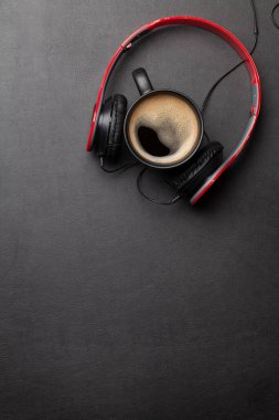 Siyah deri masanın üstünde kulaklık ve kahve fincanı. Müzik konsepti. Kopyalama alanı olan üst görünüm