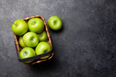 Koyu yeşil elma meyveleri sepetin içinde, siyah taş masada. Kopyalama alanı olan üst görünüm. Düz yatıyordu