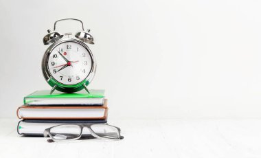 Ofis çalışma masası, malzeme ve çalar saatle dolu. Sabah ya da teslim tarihi konsepti. Metnin için boşluk ile