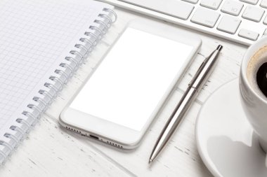 Ofis masasında bilgisayar, akıllı telefon, not defteri ve kahve. Metnin ya da uygulaman için alanı olan üst görünüm