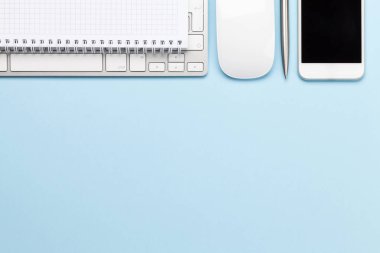 Bilgisayarı, akıllı telefonu ve malzemeleri olan mavi çalışma masası. Metnin ya da uygulaman için en üstteki görünüm. Düz yatıyordu