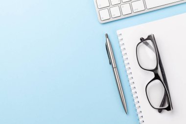 Bilgisayar, malzeme ve gözlüklü mavi çalışma masası. Metnin için en üstte boşluk var. Düz yatıyordu