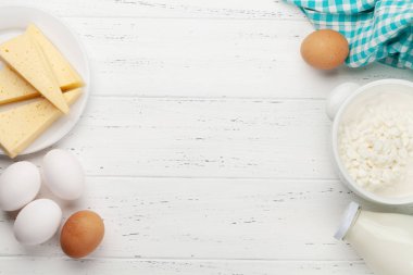 Süt ürünleri, süt, kulübe, ahşap masada peynir ve yumurta. Kopyalama alanı olan üst görünüm. Düz yatıyordu