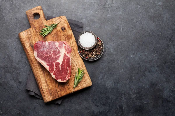 将新鲜的生牛肉牛排与调味品一起放在切菜板上 带有复制空间的顶视图平面布局 — 图库照片