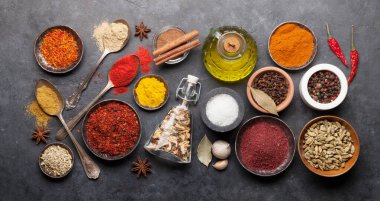 Koyu taş masada çeşitli baharatlar ve kaşıklar. Hint mutfağı. Üst görünüm düzlüğü