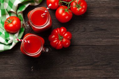 Taze domates suyu ve ahşap masada olgun domatesler. Kopyalama alanı olan üst görünüm