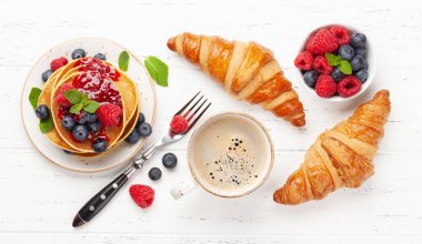 Yaz meyveleri ve reçelli nefis ev yapımı krepler kahvaltıda kruvasan ve kahve. Üst görünüm