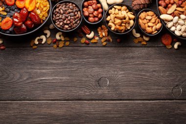 Koyu ahşap bir masada çeşitli kurutulmuş meyve ve fındıklar. Üst görünüm düzlüğü kopyalama alanı ile yatıyordu
