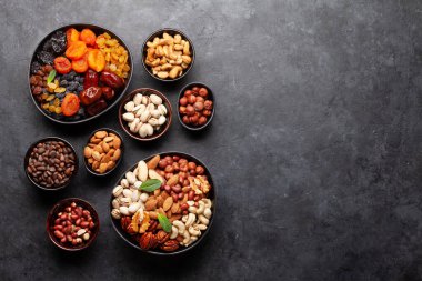 Koyu taş bir masada çeşitli kurutulmuş meyve ve fındıklar. Üst görünüm düzlüğü kopyalama alanı ile yatıyordu