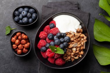 Ev yapımı granola, yoğurt ve taştan arkaplanda taze böğürtlen ile sağlıklı bir kahvaltı. Üst görünüm yakın plan