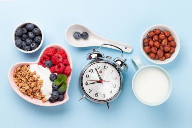 Yoğurtlu ev yapımı granola ve mavi arka planda taze böğürtlenli sağlıklı bir kahvaltı. Sabah yemeği konsepti. Üst görünüm düzlüğü