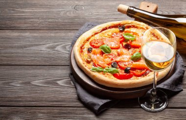 Bahçe domatesli, peynirli, somon balıklı ve fesleğenli ev yapımı deniz ürünleri pizzası. Beyaz şarap ve fotokopi alanı