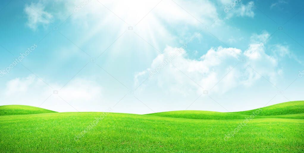 Green grass field and blue sky with bright sun summer landscape background