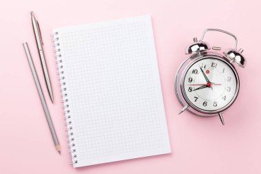 Pembe çalışma masası, malzeme ve çalar saatle dolu. Sabah ya da teslim tarihi konsepti. Metnin için en üstte boşluk var. Düz yatıyordu