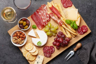 Peynir, et, üzüm ve zeytinli antipasto. Aperatif tabağı ve kırmızı beyaz şaraplı bardaklar. Üst Manzara. Düz yatıyordu