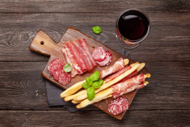 Çeşitli et antipasto 'ları. Aperatif seçme tahtası ve kırmızı şaraplı bardak. Üst Manzara. Düz yatıyordu