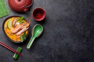 Tom Yum geleneksel Tayland çorbası deniz ürünleri, mantar, hindistan cevizi sütü ve sıcak baharatlı. Yeşil çaydanlık ve kase ile. Kopyalama alanı olan üst görünüm
