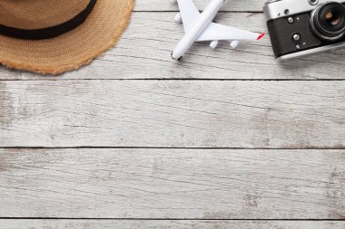 Seyahat konsepti şapka, kamera ve uçak oyuncaklarıyla ahşap masada. Üst görünüm düzlüğü kopyalama alanı ile yatıyordu